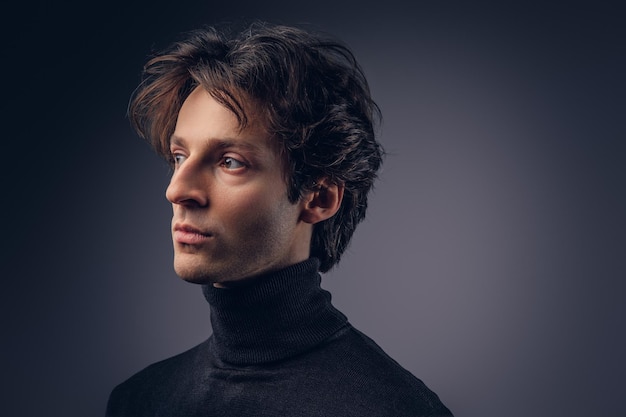 Foto gratuita retrato de un hombre sensual carismático en suéter negro. personalidad creativa. aislado en un fondo oscuro.