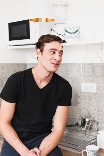 Retrato de un hombre sentado en el mostrador de la cocina