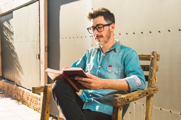 Retrato de un hombre sentado en una silla leyendo el libro