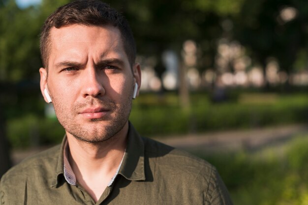 Retrato del hombre serio que lleva el auricular inalámbrico que mira la cámara