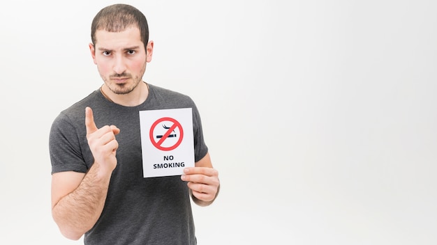Retrato de un hombre serio que lleva a cabo la muestra de no fumadores que señala el dedo hacia la cámara