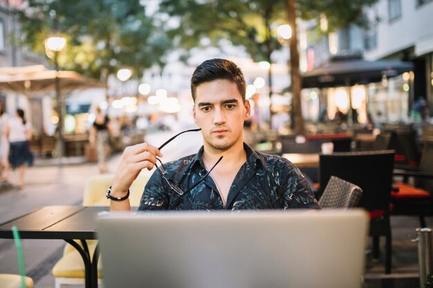 Retrato de un hombre serio que mira la pantalla del ordenador portátil en el café