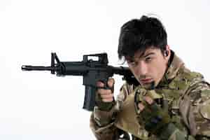 Foto gratuita retrato de hombre soldado en uniforme militar con ametralladora pared blanca