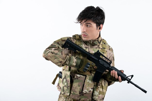 Retrato de hombre soldado en uniforme militar con rifle pared blanca