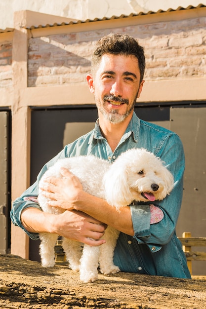 Retrato de un hombre sonriente abrazando a su perro blanco