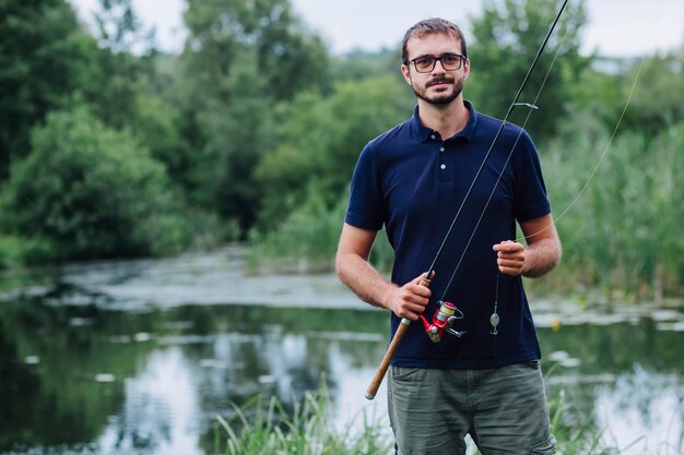 Retrato de hombre sonriente con caña de pescar cerca del lago