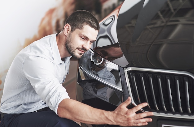 Retrato de un hombre sonriente feliz que elige un coche nuevo en la cabina.