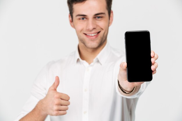 Retrato de un hombre sonriente feliz que muestra la pantalla en blanco