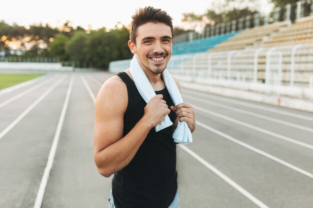Retrato de un hombre sonriente de fitness con una toalla sobre los hombros