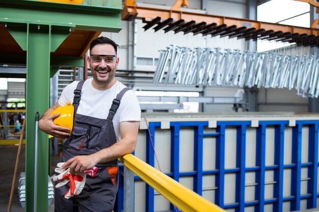 Retrato de hombre sonriente obrero de pie en la sala de producción industrial