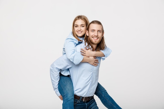 Retrato de hombre sonriente que da a mujer feliz un paseo en cuestas