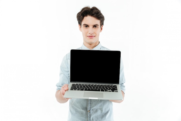 Retrato de un hombre sonriente que muestra la computadora portátil de pantalla en blanco