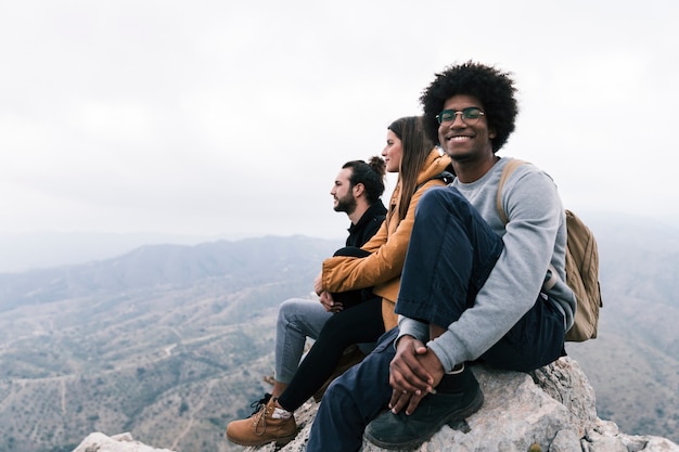 Retrato de un hombre sonriente sentado en la parte superior de la roca disfrutando con su amigo