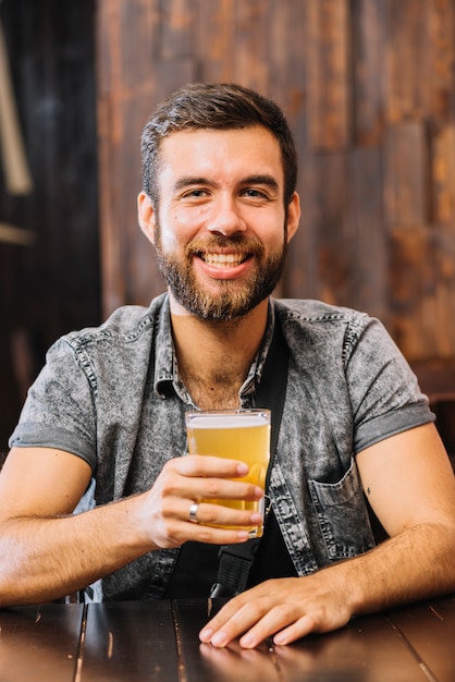 Retrato de un hombre sonriente sosteniendo un vaso de cerveza