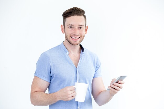 Retrato de hombre sonriente con la taza y el teléfono inteligente