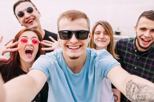 Foto gratuita retrato de hombre sonriente tomando selfie con amigos