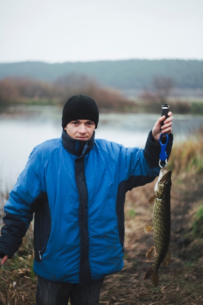 Retrato de un hombre sosteniendo pescado lucio mirando a cámara