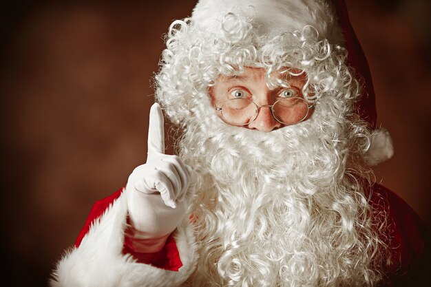 Retrato de hombre en traje de Santa Claus con una lujosa barba blanca, sombrero de Santa y un traje rojo en rojo