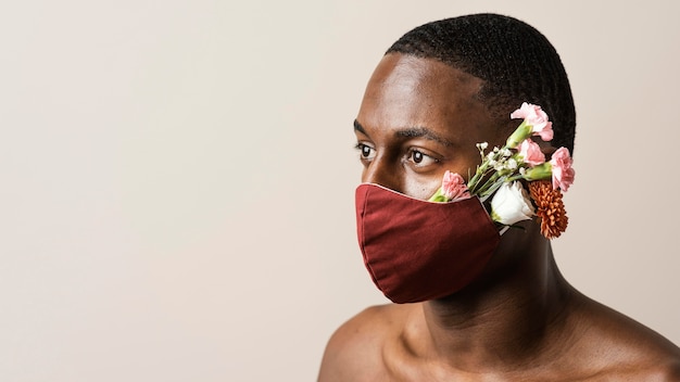 Retrato de hombre vestido con mascarilla y flores con espacio de copia