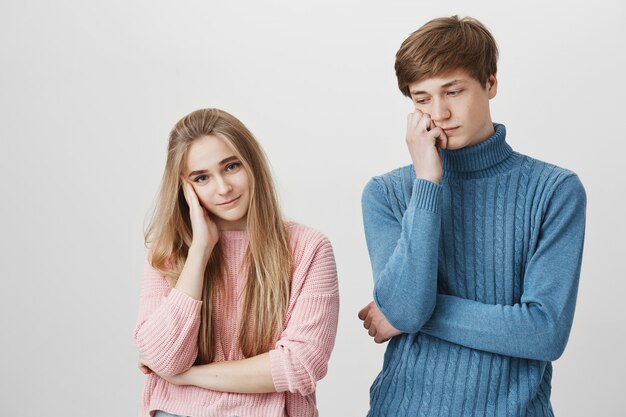 Retrato horizontal de una pareja molesta en suéteres de punto coloridos que tienen algunos problemas en su familia