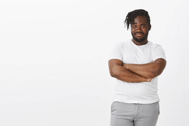 Foto gratuita retrato de indiferente chico impresionado con trenzas posando contra la pared blanca