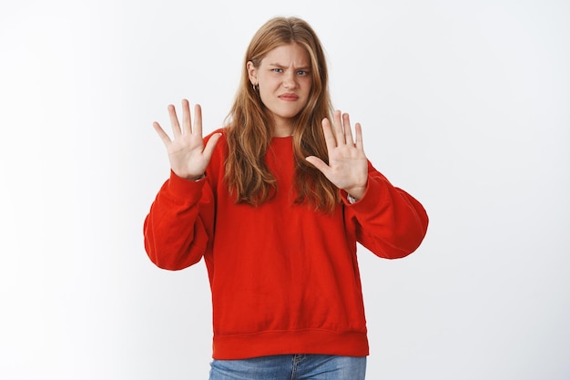 Retrato de una intensa joven disgustada y disgustada con el pelo rojo y las pecas dobladas hacia atrás por la aversión levantando las palmas