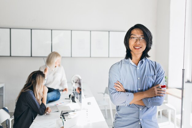 Retrato interior de empleados internacionales con sonriente hombre asiático en primer plano