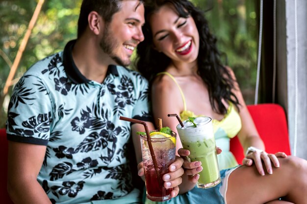 Retrato interior de feliz pareja elegante disfrutando de su cita romántica, bebiendo sabrosas bebidas alcohólicas dulces, ropa elegante, restaurante de lujo.