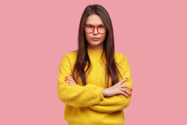 Retrato de interior de mujer joven hermosa seria con expresión estricta de confianza se siente enojado después de la pelea con el jefe, mantiene los brazos cruzados