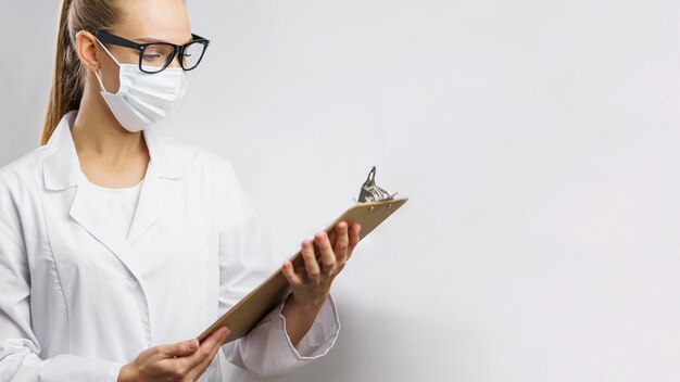 Retrato de investigadora en el laboratorio con máscara médica y portapapeles