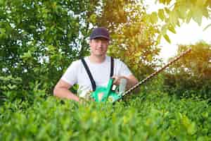 Foto gratuita retrato de jardinero profesional sosteniendo recortadora trabajando en el patio
