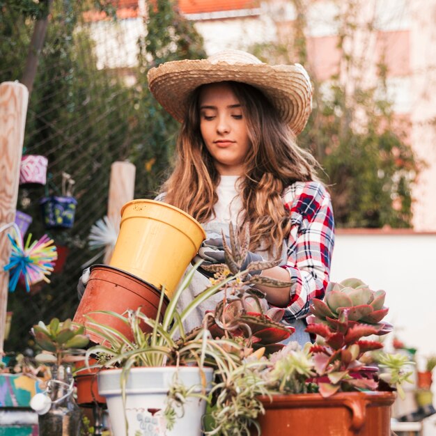 Retrato de un jardinero de sexo femenino que lleva el sombrero que mira el pote floreciente vacío