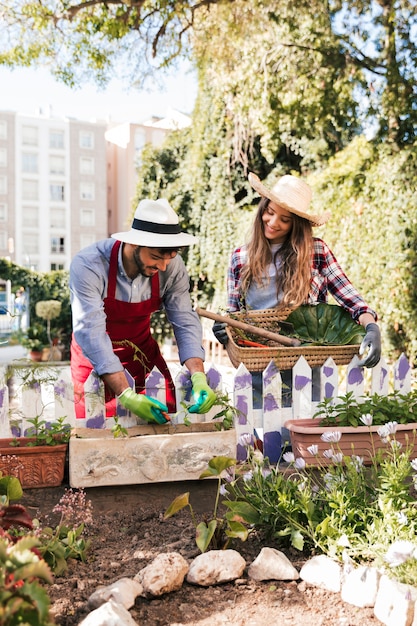 Retrato del jardinero de sexo masculino y de sexo femenino sonriente que trabaja en el jardín