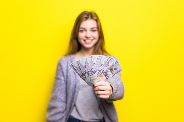 Retrato de una joven adolescente casual sosteniendo billetes de dinero aislado