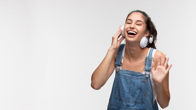 Retrato de joven adolescente en monos escuchando música con auriculares