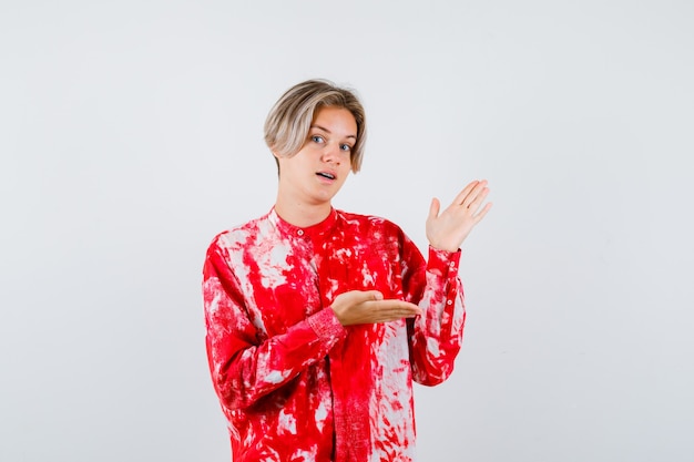 Retrato de joven adolescente mostrando gesto de bienvenida en camisa y mirando confiado vista frontal