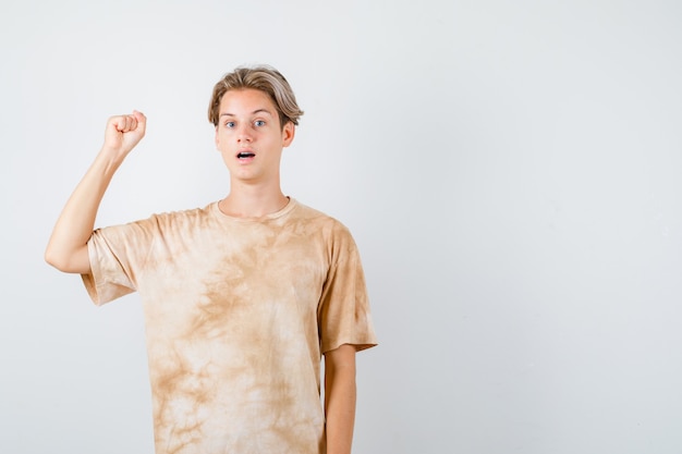 Retrato de joven adolescente mostrando gesto ganador en camiseta y mirando afortunado vista frontal