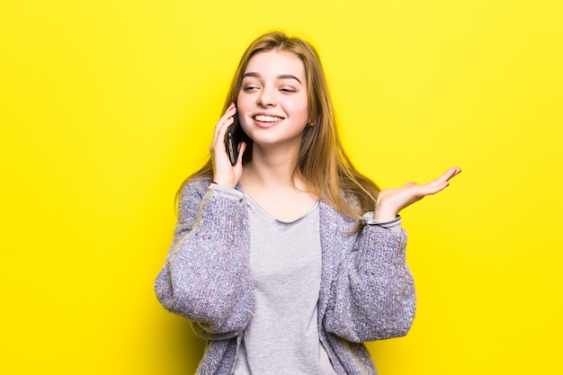 Retrato de una joven adolescente sonriente con tirantes hablando por teléfono móvil aislado