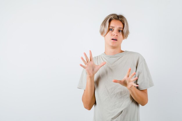 Retrato de joven adolescente tratando de bloquearse a sí mismo con las manos en la camiseta y mirando asustado vista frontal