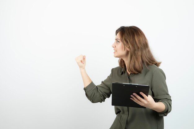 Retrato de una joven adorable con portapapeles discutiendo con alguien. foto de alta calidad