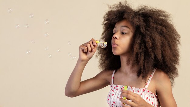 Retrato de joven adorable posando mientras juega con pompas de jabón