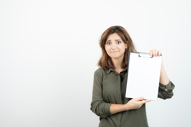 Retrato de una joven adorable que muestra un portapapeles en blanco. foto de alta calidad