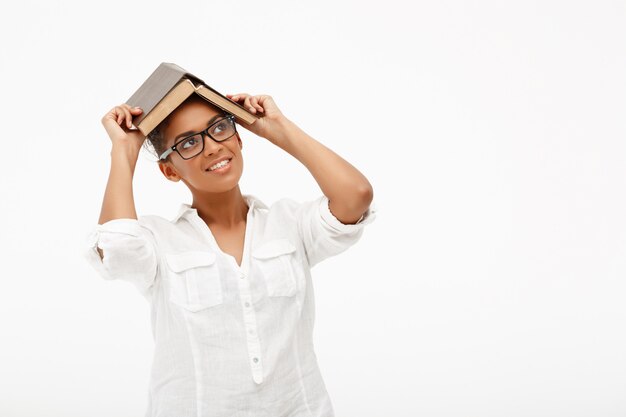 Retrato de joven africana con libro sobre pared blanca