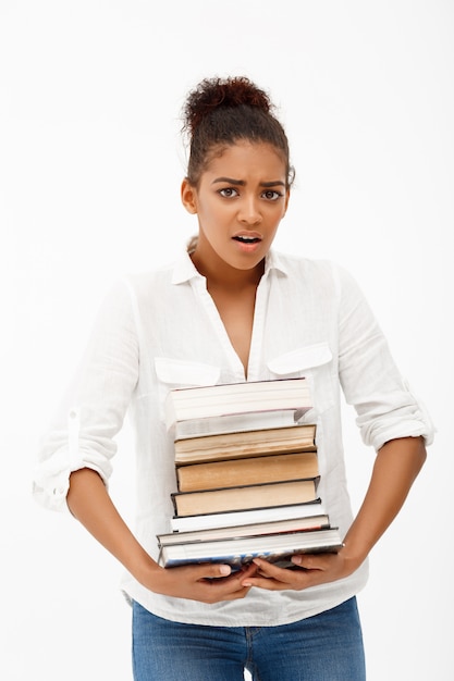 Retrato de joven africana con libros sobre pared blanca