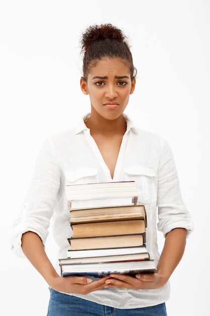 Retrato de joven africana con libros sobre pared blanca