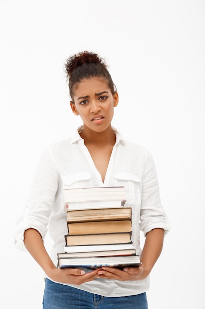 Retrato de joven africana con libros sobre pared blanca