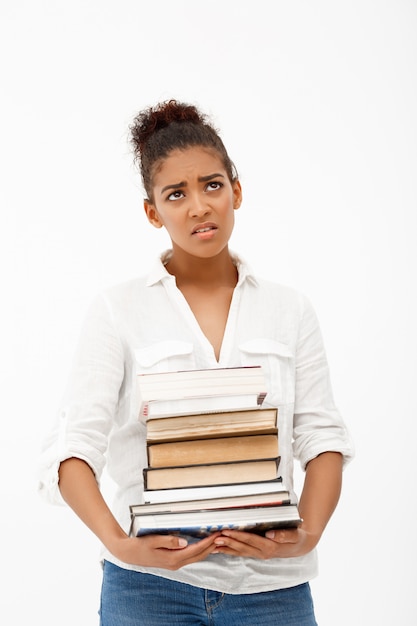 Retrato de joven africana con libros sobre pared blanca