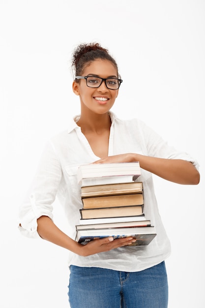 Retrato de joven africana con libros sobre pared blanca