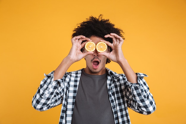 Retrato de un joven africano divertido con rodajas de naranja