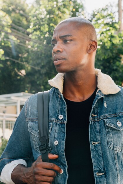 Retrato de un joven africano con mochila en su hombro mirando lejos